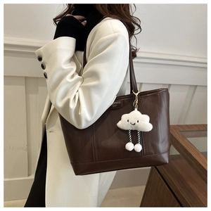 Detail of dark brown tote bag with vertical texture and cute cloud charm pendant