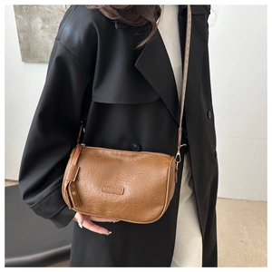 Close-up of vintage brown pleated leather bag with fashion tag and side tassel details