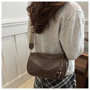 Detail of vintage brown crossbody bag with woven strap and fashion leather patch