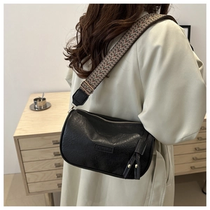 Detail of black pebbled leather crossbody bag with ethnic style wide woven shoulder strap
