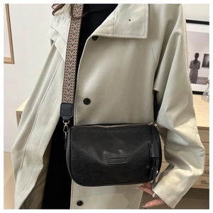 Detail of black crossbody bag featuring FASHION embossing and vintage woven strap
