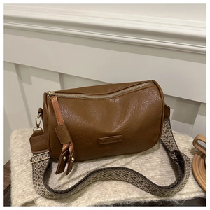 Brown Boston cylinder crossbody bag with vintage geometric strap and lychee leather texture