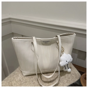 Close-up of cream white tote bag with vertical texture and cloud plush charm