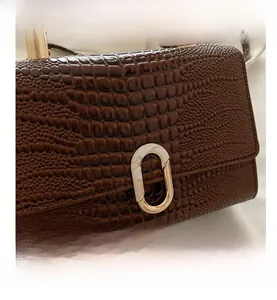 Macro detail of brown crocodile texture leather bag with elegant gold oval twist lock