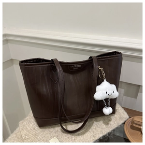 Detail of dark brown tote bag texture with a cute white plush cloud charm accessory