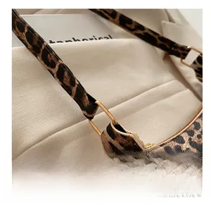 Close-up of golden metal ring buckle on leopard print shoulder bag with canvas texture