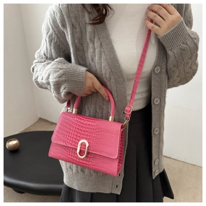 Close-up of magenta crocodile texture bag with gold twist lock and elegant crossbody strap