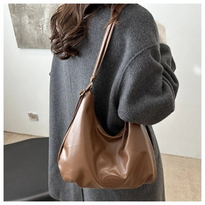Detail view of large brown soft PU leather tote bag with oval logo patch and shoulder strap