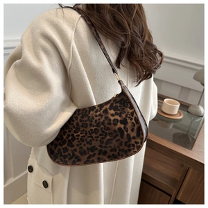 Dettaglio della borsa hobo leopardata con finiture dorate indossata su un cappotto