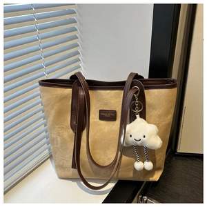 Detail view of khaki canvas tote with brown leather trim and cloud plush charm