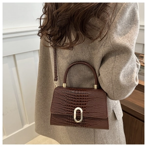 Detail of vintage brown crocodile texture handbag with gold buckle on a model