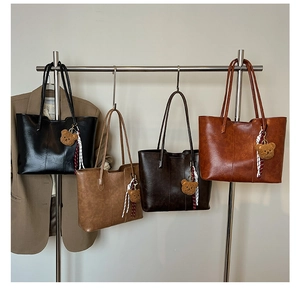 Four leather tote bags in black, tan, and brown featuring cute plush bear charms