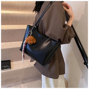 Detail of black matte PU leather tote bag with cute teddy pendant and shoulder strap