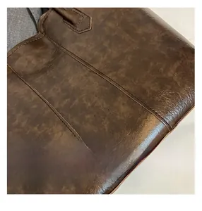 Detailed close-up of dark brown vintage leather texture and reinforced stitching on tote bag