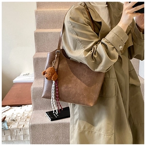 Close-up of brown vintage tote bag with plush dog charm and woven rope detail