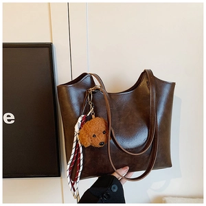 Detail of dark brown faux leather tote bag with teddy charm and striped silk scarf