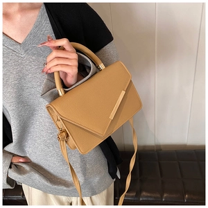 Detail of light brown pebble leather handbag with gold metal clasp and crossbody strap