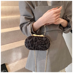 Detail van luipaardprint clutch met gouden ronde handgreep en elegante striksluiting