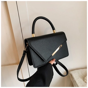 Detail of black lychee texture leather handbag with elegant gold metal accent bar