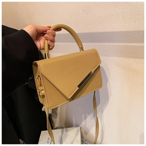 Detail of light brown lychee grain leather crossbody bag with golden metal buckle and handle