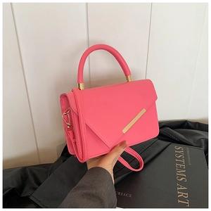 Detail einer leuchtend rosa Handtasche aus Litchi-Leder mit goldenem Metall und Gurt