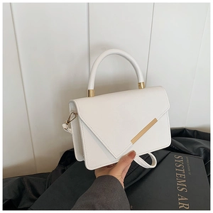 Detail of white PU leather bag featuring envelope flap and golden metal bar accent