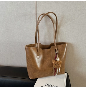 Detailed view of brown tote bag with vintage texture and cute plush bear charm