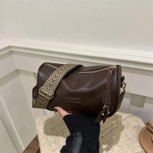 Vintage dark brown barrel bag with a wide ethnic style woven strap and gold metal hardware