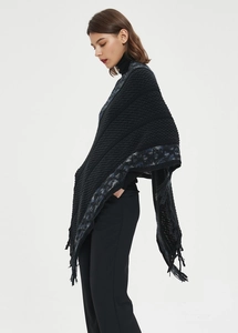 Detalle del poncho de punto con ribete de jacquard de leopardo y flecos laterales