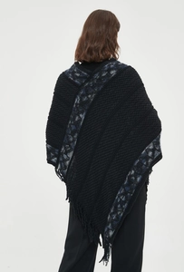 Detalle de chal negro de punto con estampado jacquard retro y flecos largos de borlas