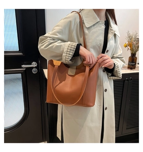 Detail shot of a brown leather tote bag with magnetic closure and clean stitching details