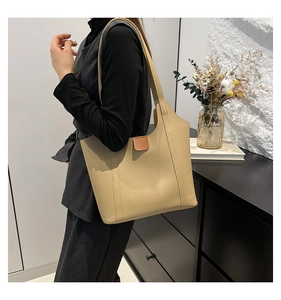 Minimalist beige tote bag featuring a brown leather flap and large capacity for commuting