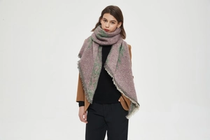 Close-up of thick knit winter scarf with tassel edges and green pine tree patterns