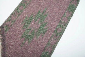 Detail of purple and green knitted scarf with geometric jacquard and frayed edges