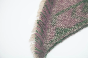 Close-up of thick winter scarf featuring purple and green knit patterns with fringe detail