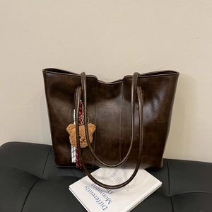 Vintage brown leather tote bag with a cute bear charm and woven rope decoration