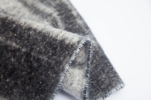 Macro detail of thick curly yarn scarf showing soft gradient grey jacquard fabric texture