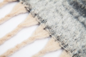 Macro detail of thick jacquard gradient scarf with soft chunky tassels and mohair texture