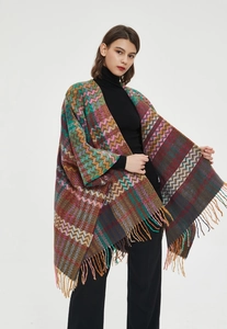 Close-up of knit shawl with colorful geometric patterns and decorative fringe edges