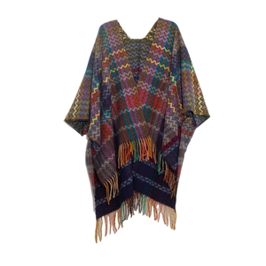 Detail of colorful zigzag knit poncho shawl with bohemian tassels on a white background