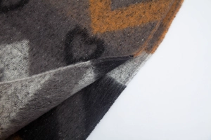 Close-up of heart jacquard knit scarf with thick loop yarn texture in charcoal and orange