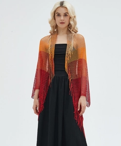 Detail of bohemian knit shawl showing orange to red gradient texture and long fringe