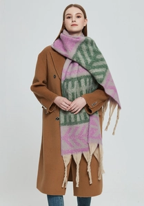 Close-up of thick knitted scarf featuring geometric patterns and long beige fringes