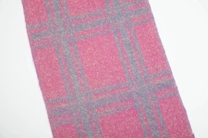 Detalle de una suave bufanda de hilo boucle con un vibrante estampado de cuadros morados