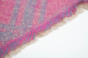Detalle de bufanda de punto geométrico rosa y azul con flecos suaves de color beige