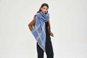 Détail de la texture à carreaux bleu et lilas et des franges fines de l'écharpe d'hiver