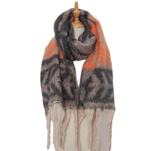 Detailed view of thick knit scarf featuring gray geometric patterns and orange tassels