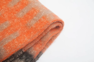 Detailed macro view of vibrant orange and beige leaf jacquard knit texture on thick scarf