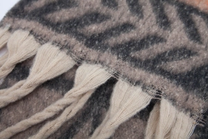 Macro shot of thick faux mohair knit scarf featuring leaf pattern and chunky tassel fringe