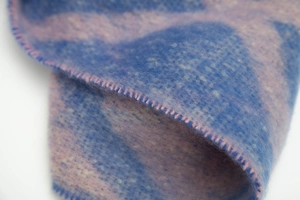 Détail de la couture feston rose sur l'écharpe en maille à carreaux bleu et rose